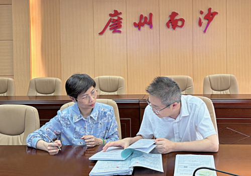 区小平（左）与资深调解员讨论案情。